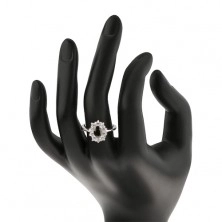 Prstan srebrne barve, črn ovalen cirkon, obrobljen z okroglimi prozornimi cirkoni